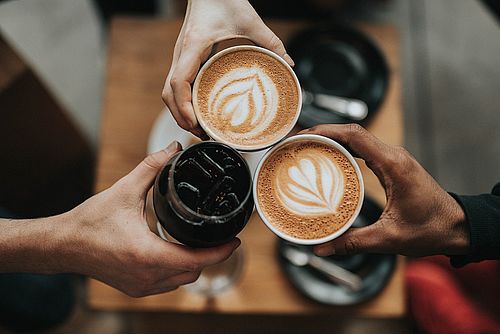 Eine Gruppe von Leuten, die ihre Kaffeetassen zusammenhalten